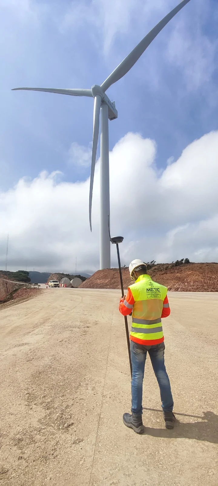 Un géomètre sur le terrain, au pied d’une éolienne